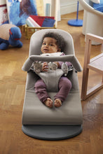 
                        
                          Load image into Gallery viewer, Child in a baby bouncer on a wooden floor with toys in the background
                        
                      