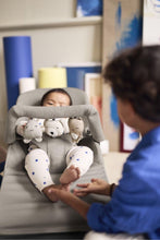 
                        
                          Load image into Gallery viewer, Child in a baby bouncer with plush toys, watched by an adult in a blue shirt.
                        
                      