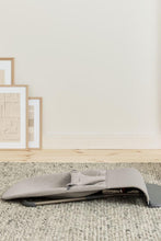 
                        
                          Load image into Gallery viewer, Gray baby bouncer on a carpeted floor with light-colored walls and framed pictures in the background.
                        
                      