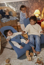 
                        
                          Load image into Gallery viewer, Two children playing with a baby in a blue bouncer in a home setting.
                        
                      